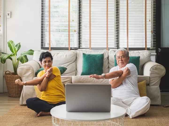 2 seniors stretching at home with a computer